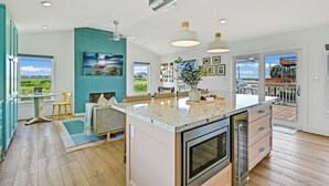 Una cocina moderna con una isla grande, horno empotrado y luces colgantes.