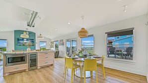Una cocina moderna con comedor, suelo de madera y ventanas amplias que ofrecen vistas al exterior.