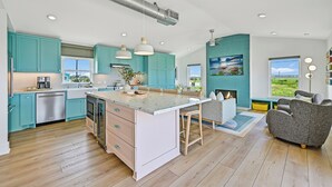 Una cocina moderna con gabinetes azul turquesa, una isla grande e iluminación colgante.