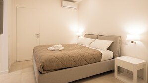 A bedroom with a bed, bedside lamps, and an air conditioning unit. - Luxury Freedom Juno (Palermo)