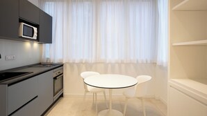 A modern kitchen with a microwave, oven, and sink. There is a round table with four chairs and a window with sheer curtains. - Luxury Freedom Juno (Palermo)