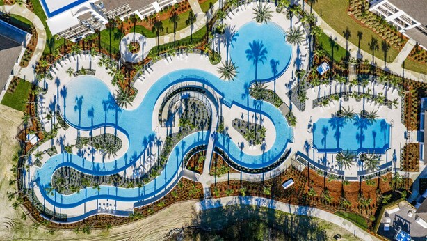 Vista aérea de um resort com uma piscina central ampla, várias piscinas menores e palmeiras.
