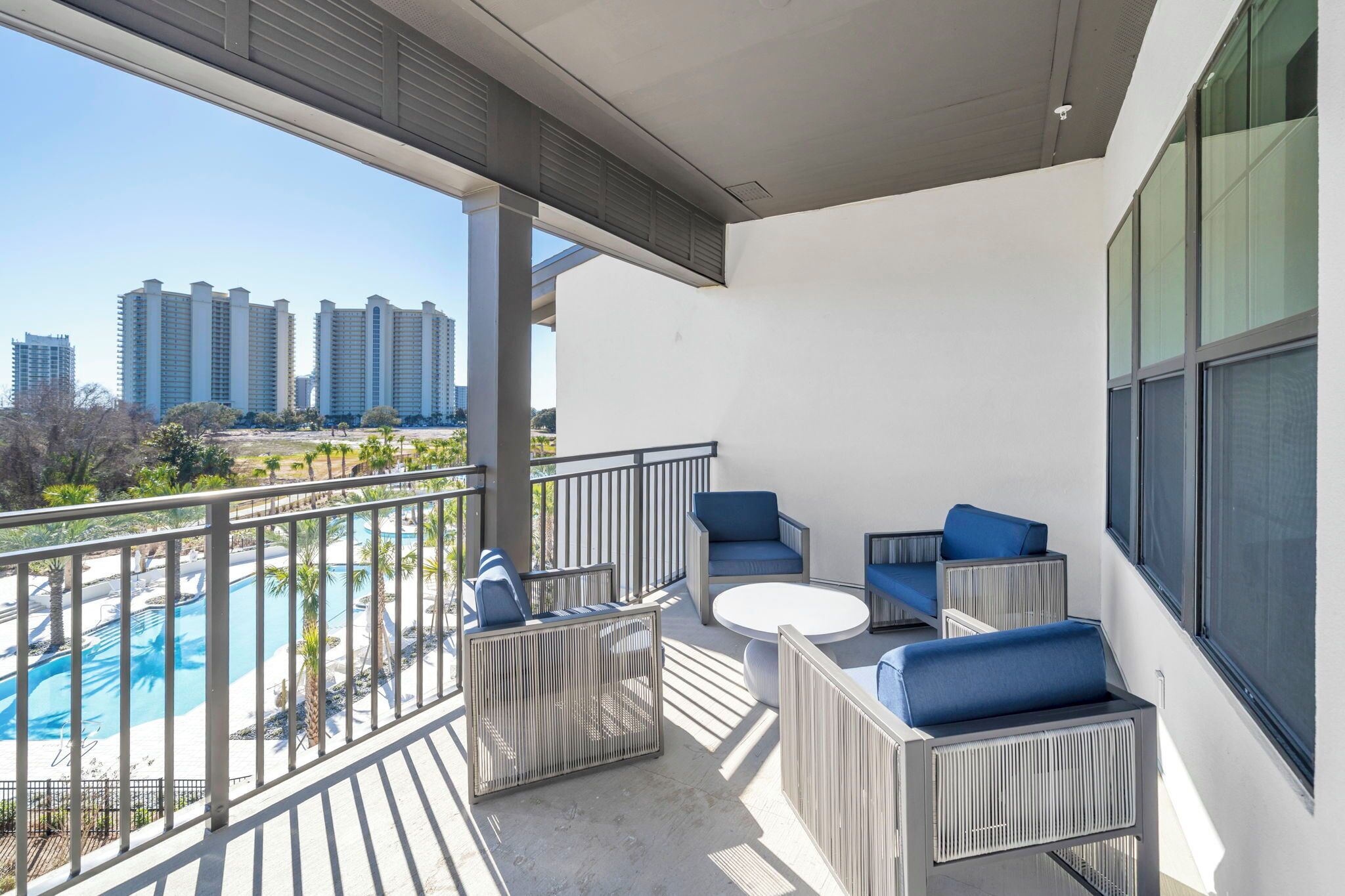 A balcony with outdoor seating, a pool, and a view of high-rise buildings.