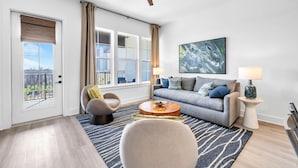 Een moderne woonkamer met een bank, fauteuil, salontafel en een plafondventilator.
