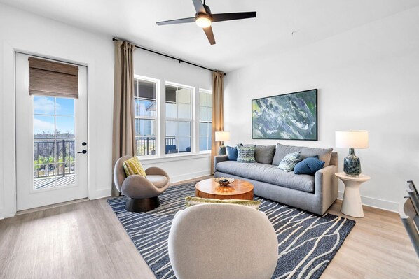 Ein modernes Wohnzimmer mit Sofa, Sessel, Couchtisch und Deckenventilator.
