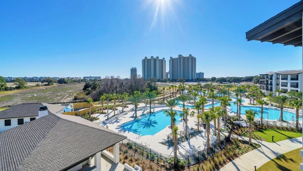 Een resort met een zwembad, palmbomen en hoge gebouwen op de achtergrond.