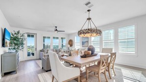 A spacious living room with a large dining table, comfortable seating, and a view of the outdoors.