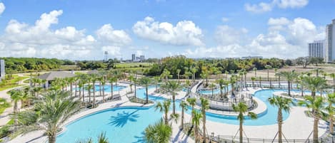 Un resort con varias piscinas, palmeras y un cielo despejado.
