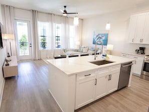 Eine moderne Küche mit Kochinsel, weißen Schränken und einem Essbereich mit einer Couch.