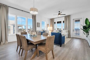 Ein modernes Wohnzimmer mit Esstisch, Stühlen, einer Couch und einem Deckenventilator.