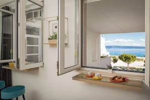 Ein modernes Zimmer mit einem großen Fenster mit Blick auf eine schöne Meerlandschaft und eine ferne Stadt.
