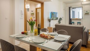 En matplats med ett glasbord för fyra personer, en soffa och ett fönster med utsikt.