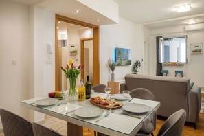 Ein Essbereich mit einem Glastisch, gedeckt für vier Personen, einer Couch und einem Fenster mit Blick.