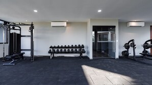 Une salle de sport équipée de matériel de musculation, d’haltères et d’un banc.