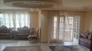 Ein geräumiges Wohnzimmer mit großem Teppich, einer Sofagarnitur und einem Sessel.