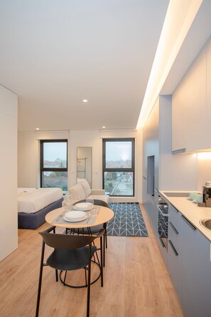 Ein modernes Hotelzimmer mit Essbereich, einer Couch, einem Bett und Blick auf die Stadt.