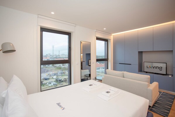 Ein modernes Hotelzimmer mit einem großen Bett, einer Couch und einem Fernseher an der Wand.