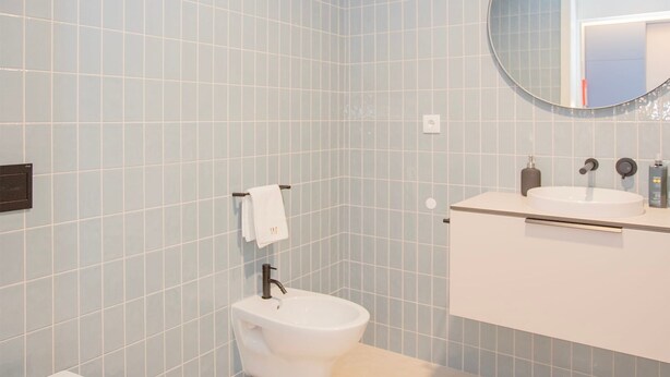 Un bagno moderno con WC, bidet, lavandino e specchio.