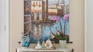 A hallway with a painting of a Venetian canal, a console table with books, a chess set, and a potted orchid. - Luxury LA Garden Estate Private Pool Hottub Tennis (La Habra)