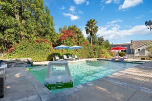 Une piscine avec un toboggan, des chaises longues et des parasols.