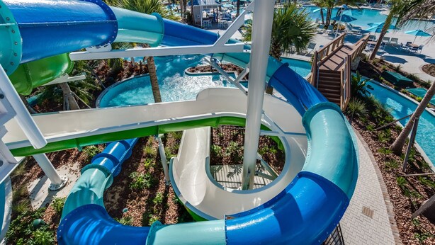 A water park with multiple slides and pools, surrounded by palm trees and lounge areas. - Stunning Resort Villa w Pool Cinema Games Room (Clermont)