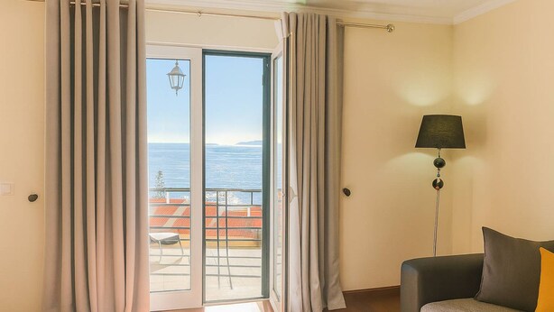 Una habitación con puerta corrediza de vidrio a un balcón, un sofá y una lámpara de pie.