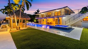 A modern house with a swimming pool, a covered outdoor area, and a staircase leading to the upper floor. - Deep Blue Waterfront Gem Pool Kayaks Dock (Key Colony Beach)