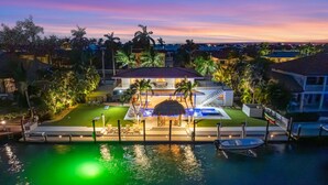 A waterfront property with a swimming pool, outdoor seating, and a staircase leading to a covered area. - Deep Blue Waterfront Gem Pool Kayaks Dock (Key Colony Beach)