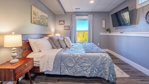 A bedroom with a bed, bedside tables, a TV, and a window with curtains. - MTN Retreat, 5 Bdrm, Pool, Hot Tub, Game Rm, Theater, Putt-Putt, Fireplace. (Dahlonega)