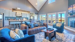 A spacious living area with a large sofa, a coffee bar, and a fireplace. - MTN Retreat, 5 Bdrm, Pool, Hot Tub, Game Rm, Theater, Putt-Putt, Fireplace. (Dahlonega)