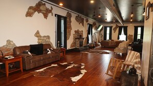A spacious living room with a stone fireplace, leather sofas, and a large wooden floor. - Historic meets modern renovation is this downtown gem. (Buffalo)