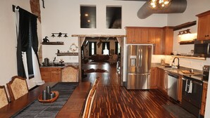 Una cocina amplia con armarios de madera, electrodomésticos de acero inoxidable y una larga mesa de comedor.