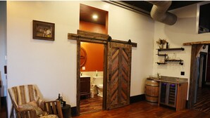 A room with a wooden rocking chair, a wooden door, a barrel, and a shelf with decorative items. - Historic meets modern renovation is this downtown gem. (Buffalo)