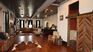 A spacious room with a wooden floor, leather furniture, and a large fur rug. - Historic meets modern renovation is this downtown gem. (Buffalo)