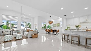 A spacious living area with a dining table, sofas, and a kitchen area with bar stools. - Waterfront Oasis Heated Pool Game Room Gym (Deerfield Beach)