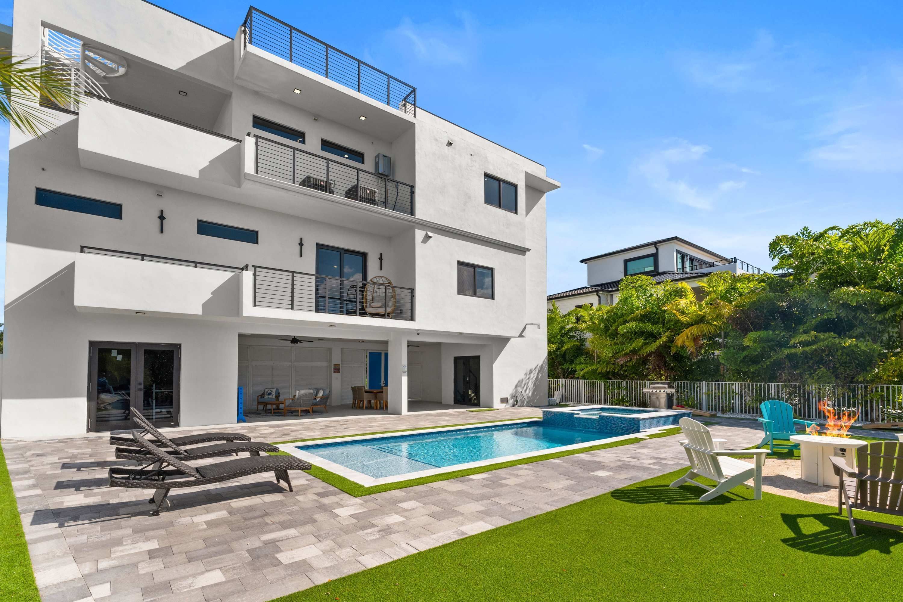 Una casa moderna de dos pisos con piscina, mobiliario exterior y césped cuidado.