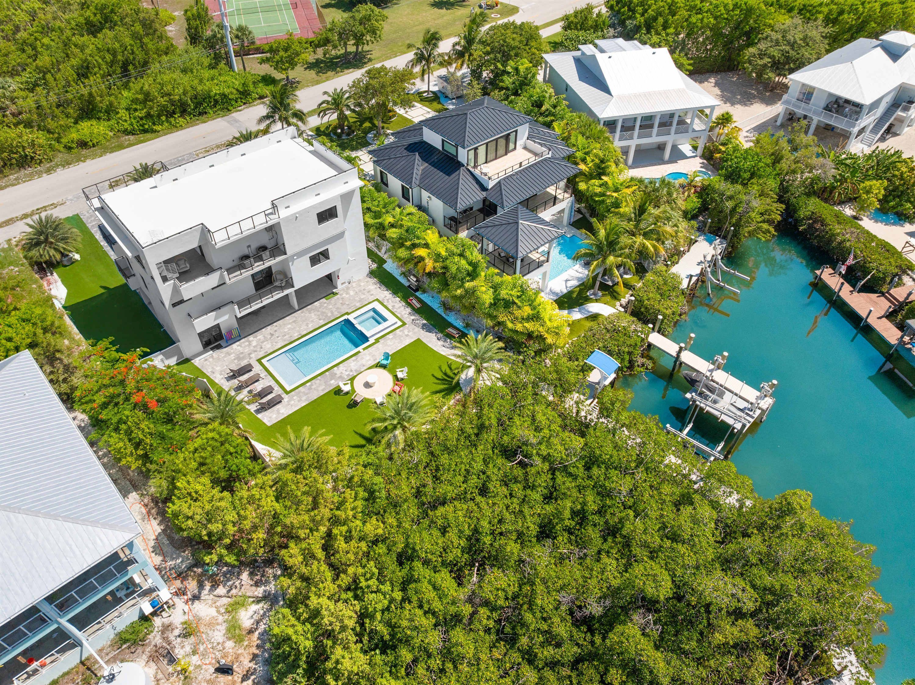 A modern multi-story building with a rooftop pool, surrounded by lush greenery and a clear blue pool.