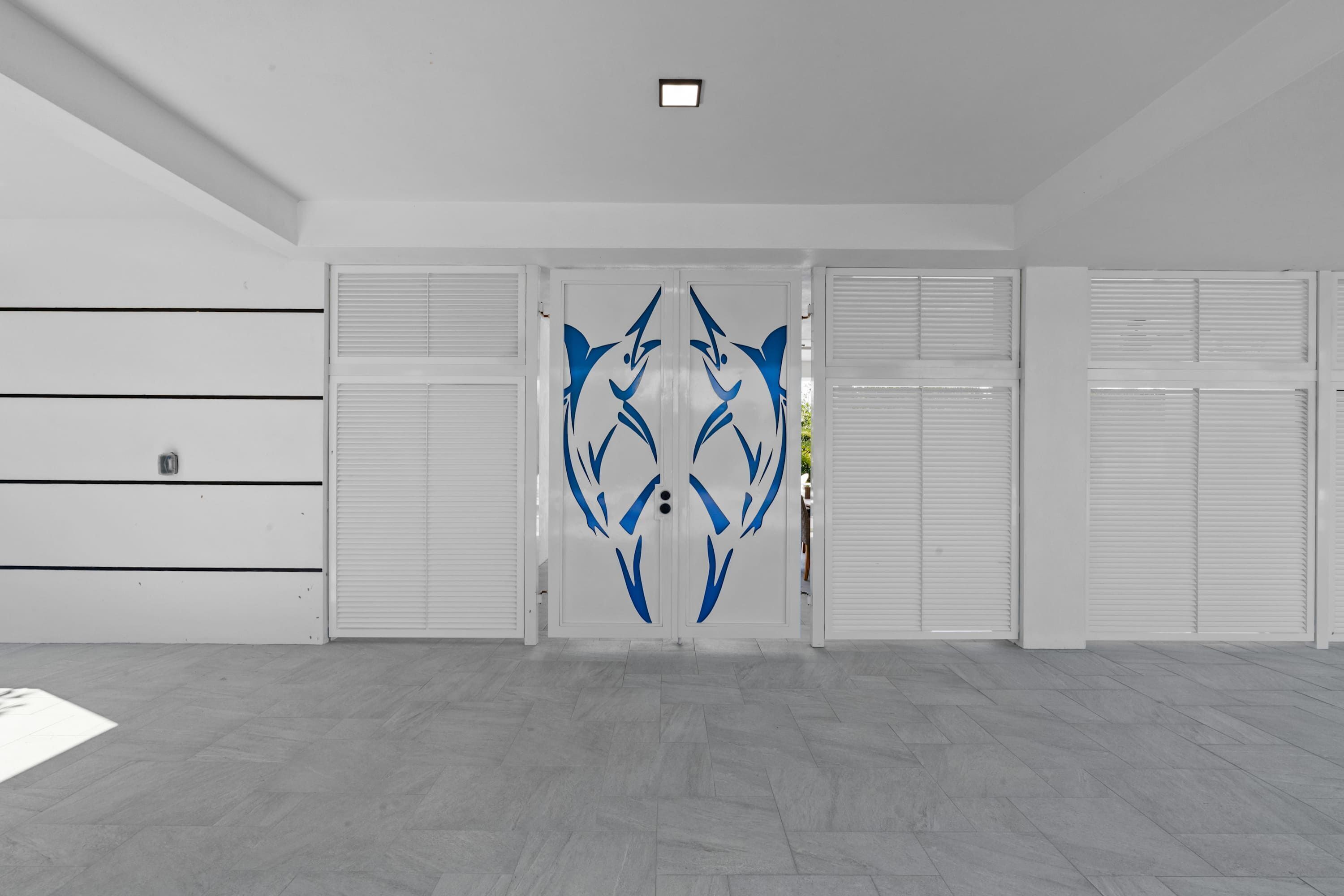 A modern interior with a large decorative glass door featuring a blue abstract design, white walls, and a tiled floor.