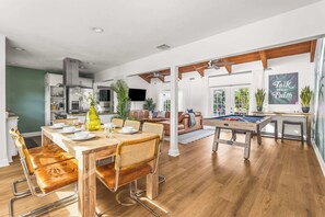 Amplia sala de estar con mesa de billar, una mesa de comedor con sillas y una cocina al fondo.