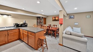 A kitchen with wooden cabinets, a granite countertop, and a coffee maker. There is a dining area with a wooden table and chairs. - Cozy Retreat With Hot Tub In Peaceful Goshen 4 Bedroom Home (Goshen)