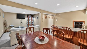 A dining area with a wooden table, chairs, and a television mounted on the wall. - Cozy Retreat With Hot Tub In Peaceful Goshen 4 Bedroom Home (Goshen)