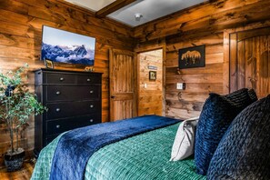 A wooden-paneled room with a bed, dresser, and a television on the wall. - Pearl's Mountain Retreat 3 Bedroom Cabin (Sevierville)