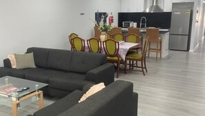 Een moderne woonkamer met een bank, een salontafel en een eethoek met stoelen en een tafel.