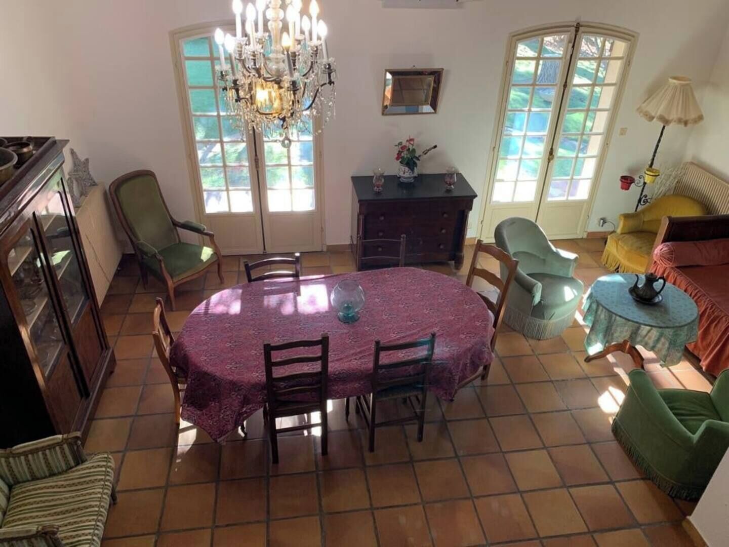 Un comedor con una mesa redonda, sillas, una araña y vistas amplias a través de grandes ventanales.