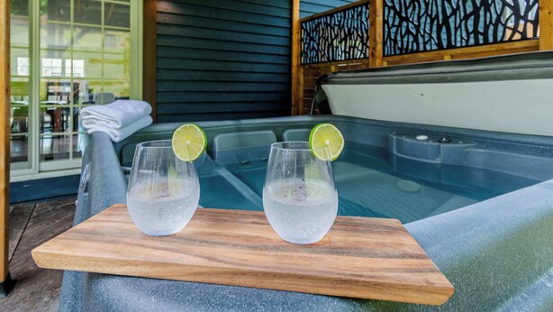 A wooden table with two glasses of water and lime slices, placed in front of a hot tub. - SPA | Entre fleuve et montagne | Chalet La Shred (Petite-Rivière-Saint-François)