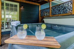 A wooden table with two glasses of water and lime slices, placed in front of a hot tub. - SPA | Entre fleuve et montagne | Chalet La Shred (Petite-Rivière-Saint-François)