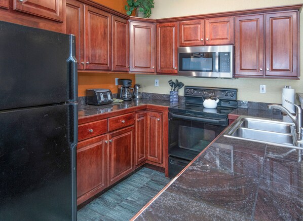 A kitchen with wooden cabinets, a stainless steel refrigerator, a microwave, a stove, and a sink. - Vail Condo Near Gondola with Mtn Views, SV12E (Vail)