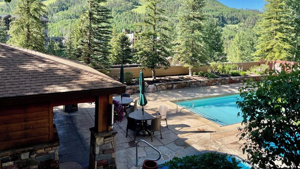 Un espace piscine doté d’une terrasse en bois, d’un patio en pierre et offrant une vue sur un paysage montagneux.