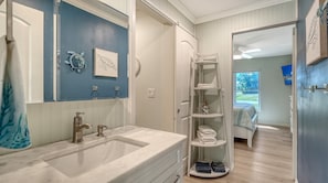 Un bagno con lavandino, specchio e portasciugamani.