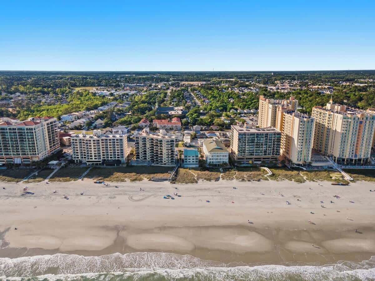 A coastal cityscape with high-rise buildings and a sandy beach.